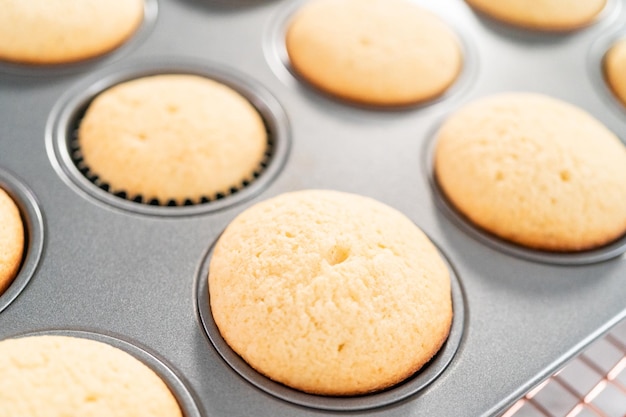 Resfriando cupcakes de baunilha recém-assados em um escorredor.