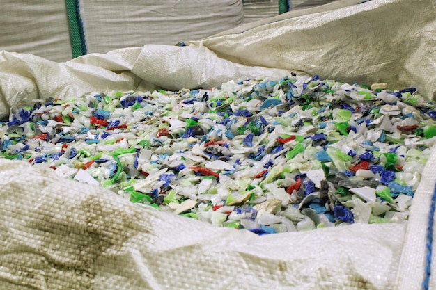 Residuos plásticos arrugados en una planta de reciclaje Flocos de botellas de plástico recicladas en una bolsa