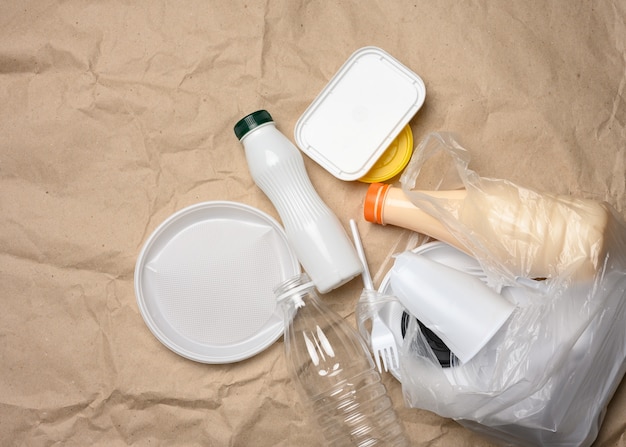 Residuos plásticos de la vida en el fondo de papel kraft marrón, contaminación ambiental, vista superior