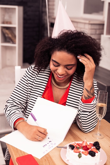 Resoluciones de cumpleaños. Mujer positiva alegre pensando qué hacer mientras crea un plan para ella