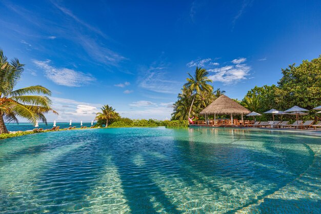 Foto resort de praia de luxo com piscina e cadeiras de praia ou espreguiçadeiras sob guarda-chuvas de palmeiras de coco