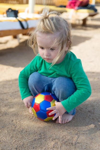 Resort-Hotel bietet Unterhaltung für Kinder Kid Kind spielen mit Ball allein Junge niedlich wollen Spaß haben Blonde Haare Baby Boy spielen mit Ball im Freien Kleinkind im Urlaub brauchen Unterhaltung