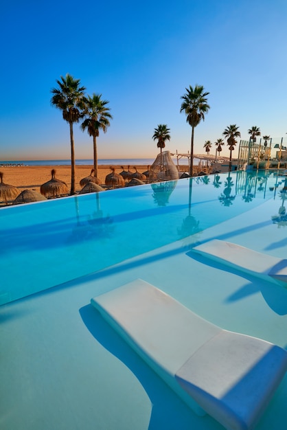 Resort piscina infinita em uma praia com palmeiras
