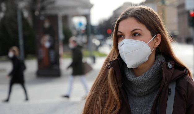 Se respeta el distanciamiento social. Retrato de mujer joven con mascarilla FFP2 KN95 en ropa de invierno al aire libre.