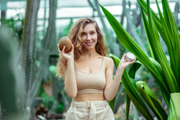 Respetuoso del medio ambiente. Mujer sosteniendo un coco y un tarro de crema en sus manos