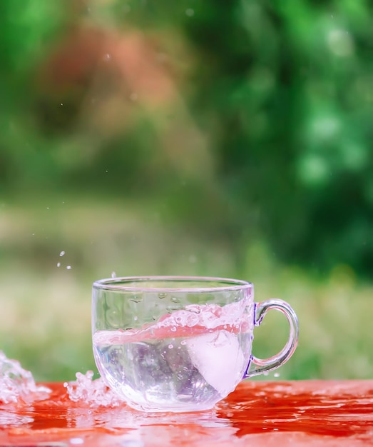 Foto respingo de água fresca fresca com cubo de gelo no copo de vidro transparente na mesa ao ar livre no dia de verão