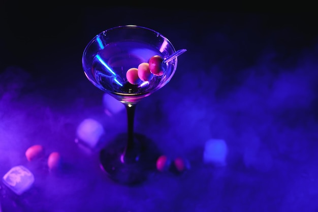 Respingo de bebida de coquetel Martini com cubos de gelo em cores neon iridescentes rosa e azul Conceito mínimo de vida de festa noturna