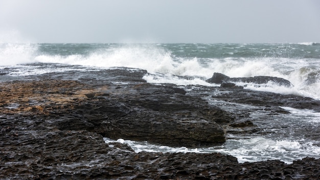 Respingo de ondas grandes em uma paisagem rochosa à beira-mar