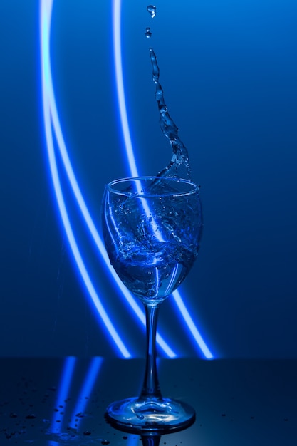 Respingos de água de uma taça de vinho no fundo azul com pequenas gotas e reflexão da bebida de ano novo