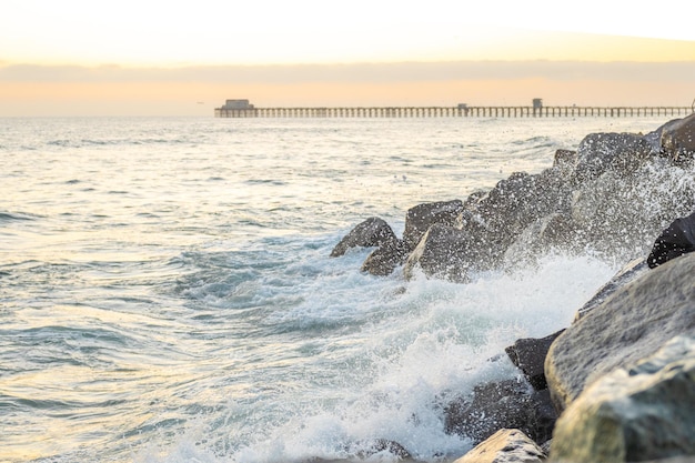 Respingos de ondas do mar batem contra rochas ao pôr do sol Estados Unidos Califórnia