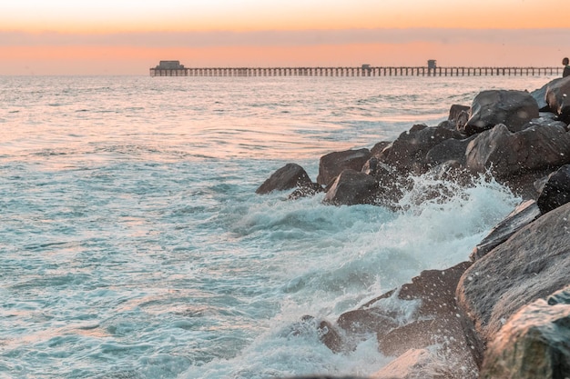 Respingos de ondas do mar batem contra rochas ao pôr do sol Estados Unidos Califórnia