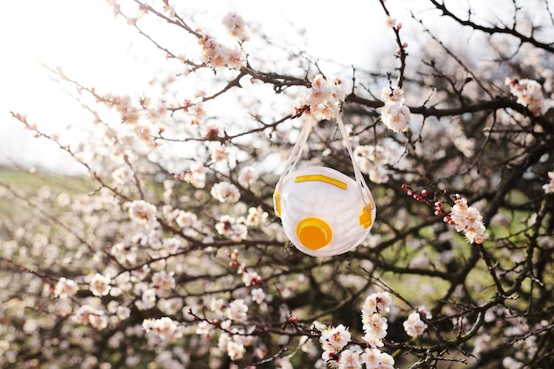 Foto respirador o máscara contra un fondo de árboles florecientes de primavera durante la pandemia del coronavirus covid