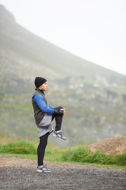 Respirando el aire fresco Longitud total de un joven corredor estirándose por la mañana y admirando la vista