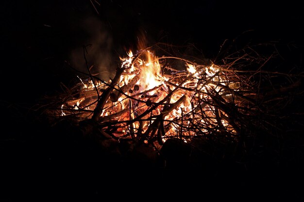 Resplandecientes palos de brasa fogata en la noche con llamas contra fondo negro