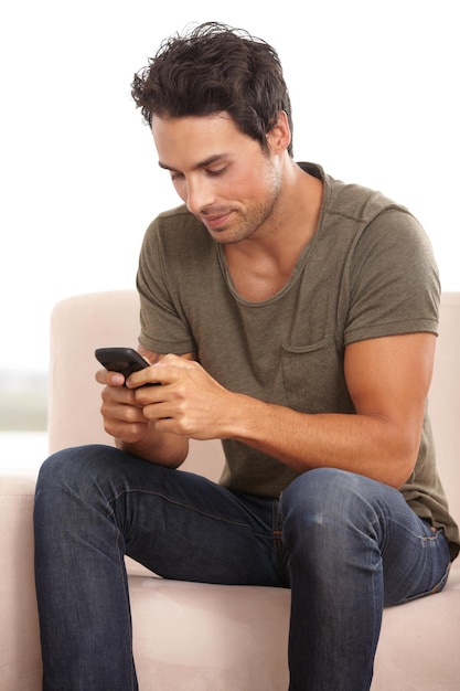 Respondiendo a un mensaje de texto Un apuesto joven sentado en su sofá y escribiendo un mensaje de texto