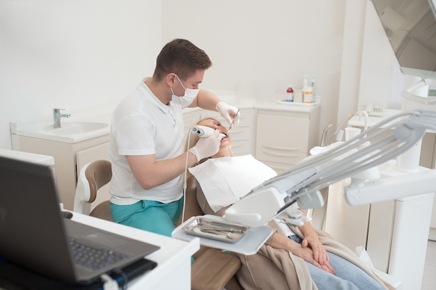 Restauración de dientes. Dentista masculino haciendo restauración de dientes a una paciente