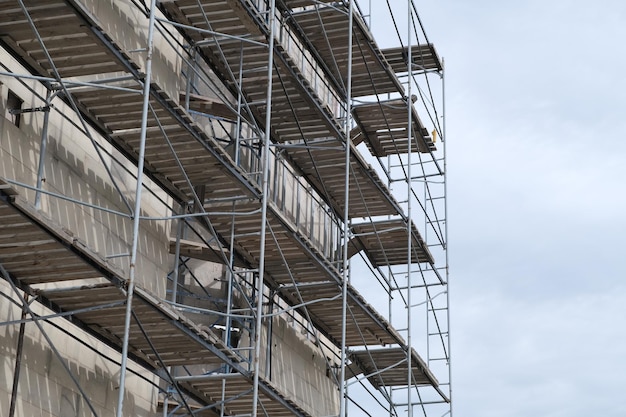 Restauración de la fachada del edificio contra el cielo nublado Reconstrucción del exterior del edificio con andamios