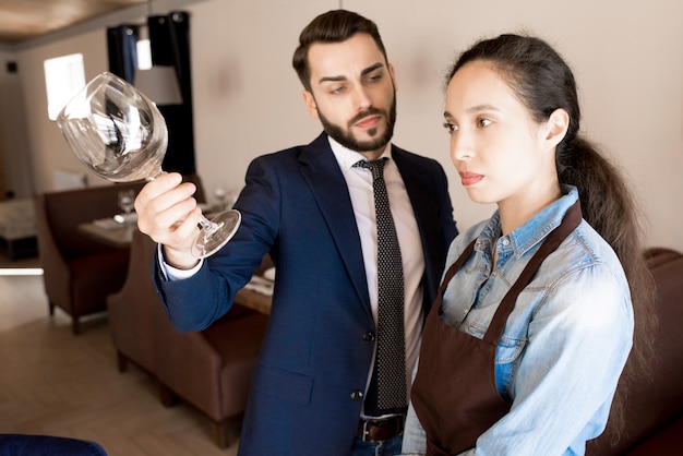 Restaurador disgustado mostrando una copa de vino sucia a la camarera