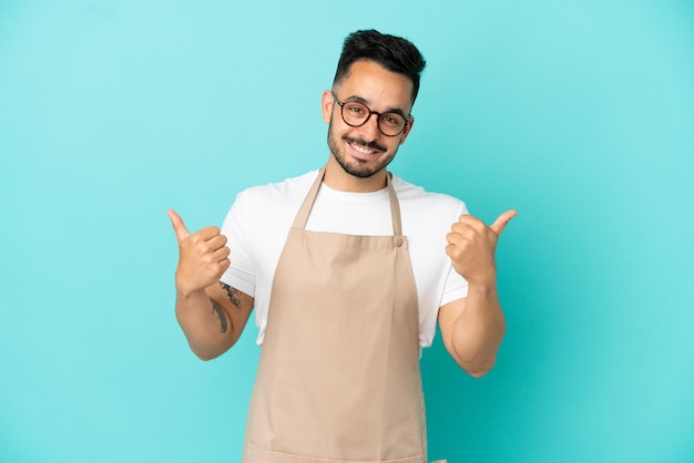 Restaurant Kellner kaukasischer Mann isoliert auf blauem Hintergrund mit Daumen hoch Geste und lächelnd