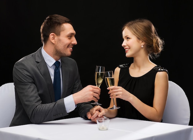 Restaurant-, Paar- und Urlaubskonzept - lächelndes Paar mit einem Glas Champagner, das sich im Restaurant ansieht