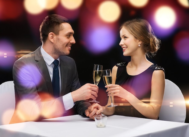 Restaurant-, Paar- und Urlaubskonzept - lächelndes Paar mit einem Glas Champagner, das sich im Restaurant ansieht