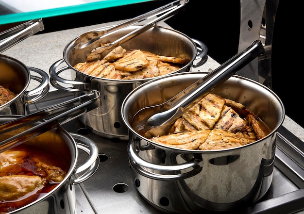 Restaurantbuffet mit Reiskochern, Bohnen, Hähnchen und Fleisch.