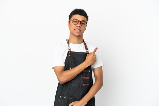 Restaurante camarero afroamericano hombre aislado sobre fondo blanco apuntando hacia el lado para presentar un producto