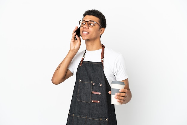 Restaurante camarero afroamericano hombre aislado sobre fondo blanco sosteniendo café para llevar y un móvil