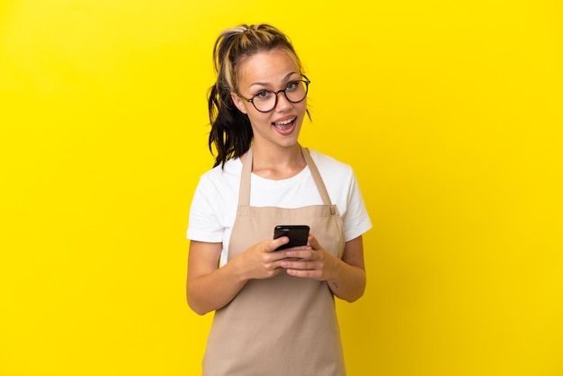 Restaurante camarero chica rusa aislada sobre fondo amarillo sorprendido y enviando un mensaje