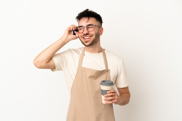 Restaurante camarero hombre caucásico aislado sobre fondo blanco sosteniendo café para llevar y un móvil