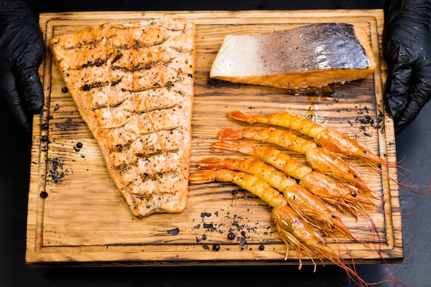 Restaurante de carnes y mariscos. Vista superior de la tabla de madera con filete de salmón ahumado y langostinos.