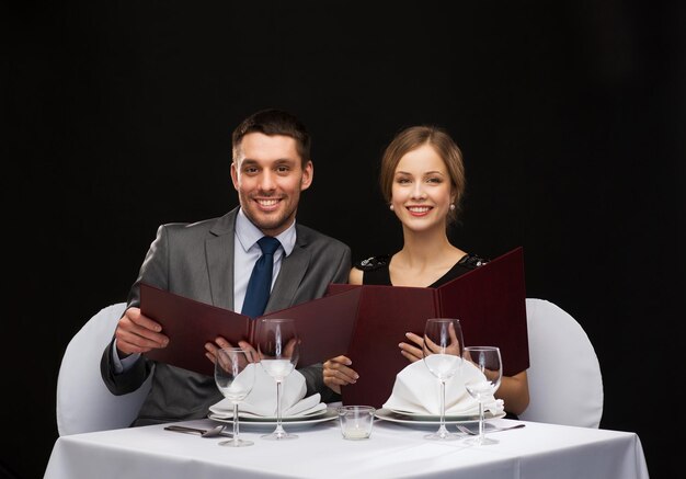 restaurante, casal e conceito de férias - casal sorridente com menus no restaurante