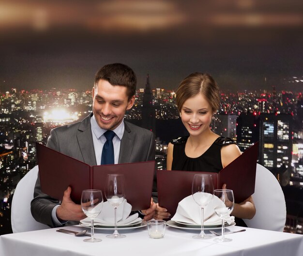 Foto restaurante, casal e conceito de férias - casal sorridente com menus no restaurante