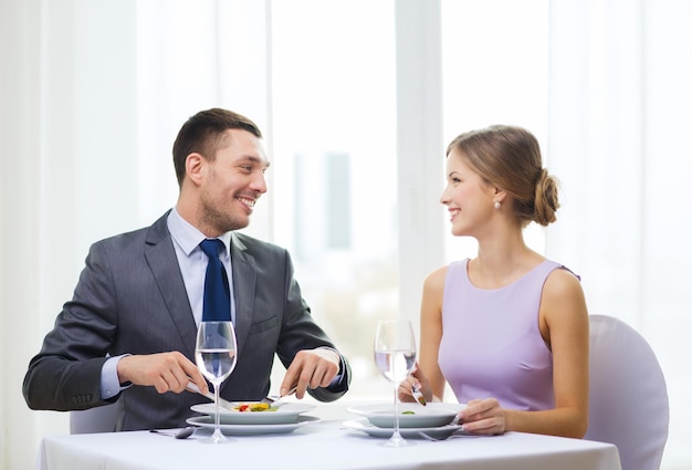 restaurante, casal e conceito de férias - casal sorridente comendo aperitivos no restaurante