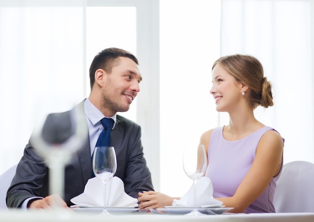 restaurante, casal e conceito de férias - casal sorridente olhando um ao outro no restaurante