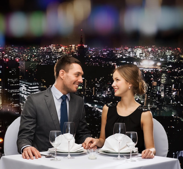 restaurante, casal e conceito de férias - casal sorridente olhando um ao outro no restaurante