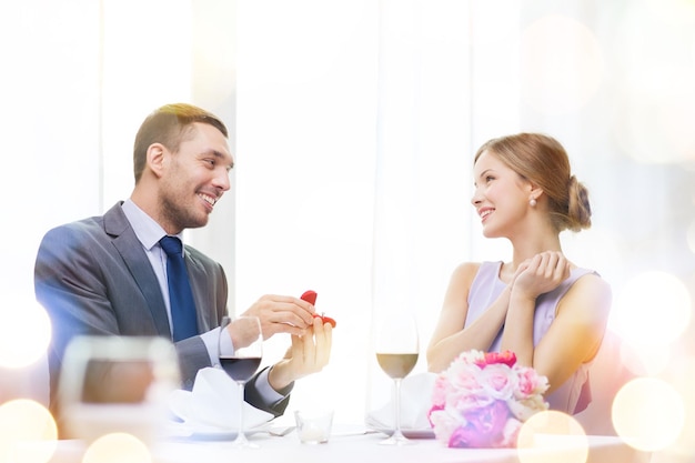 restaurante, casal e conceito de férias - homem sorridente propondo a namorada no restaurante