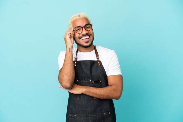 Restaurante colombiano garçom homem isolado em um fundo azul com óculos e feliz