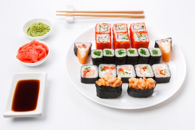 Restaurante de comida japonesa, rollos de colores, gunkan y plato de sushi. Con palillos, jengibre, wasabi y salsa de soja. Pov, aislado sobre fondo blanco.