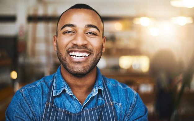 Restaurante de cafeteria e retrato de garçom negro para serviço trabalhando e feliz no café Inicialização de barista de pequeno empresário e sorriso confiante de trabalhador masculino no refeitório pronto para servir