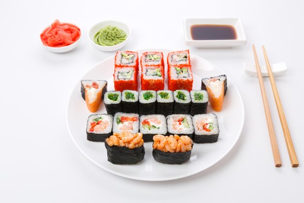 Restaurante de comida japonesa, rolinhos coloridos, prato de gunkan e sushi. conjunto com pauzinhos e molho de soja. visão pov isolada no fundo branco