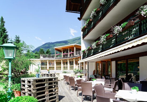 Restaurante de rua com mesas e cadeiras no hotel resort em bad kleinkirchheim na caríntia, áustria. projeto do café da calçada. estilo de vida e natureza. terraço ou varanda do café pronto para o café da manhã