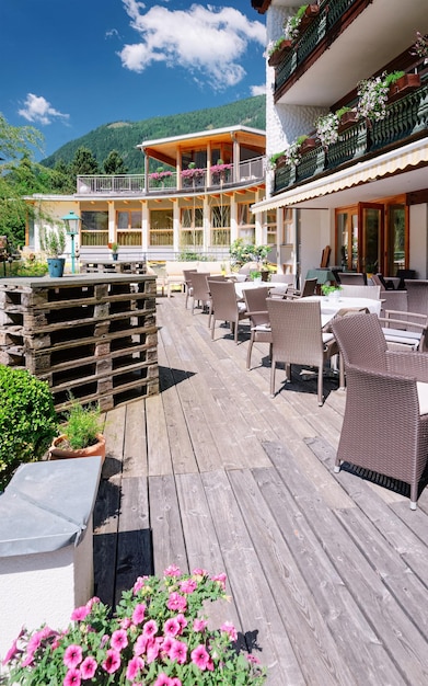 Restaurante de rua com mesas e cadeiras no hotel resort em Bad Kleinkirchheim na Caríntia, Áustria. Projeto do café da calçada. Estilo de vida e natureza. Terraço ou varanda do café pronto para o café da manhã