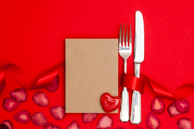 Restaurante del día de San Valentín Cuchillo y tenedor con una tarjeta de papel marrón en blanco