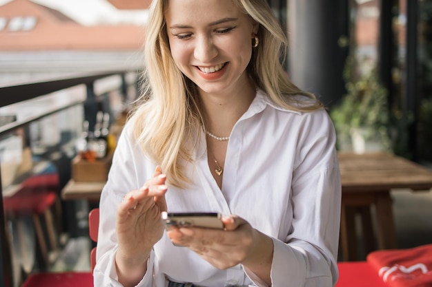 Restaurante e smartphone descontraído mulher loira digitar e rolar ou verificar e-mail e contato social