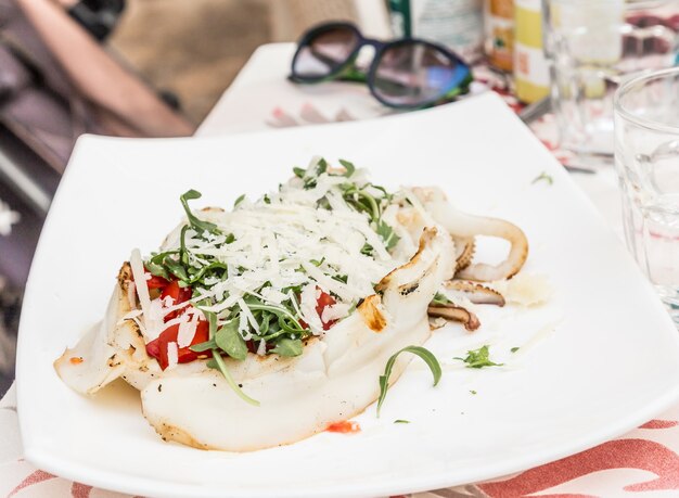 Restaurante italiano en Gallipoli, región de Puglia (sur de Italia). Sepia tradicional con ensalada fresca, tomates y auténtico queso Parmigiano. Luz.