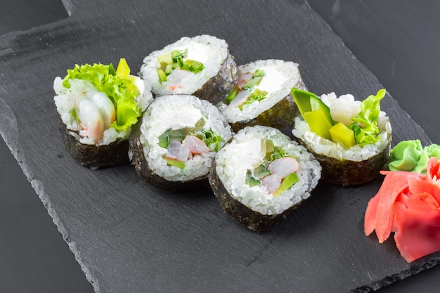 Restaurante japonés, rollo de sushi en plato de pizarra negro.