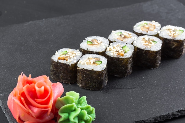 Restaurante japonés, sushi roll en placa de pizarra negra.