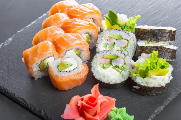 Restaurante japonés, sushi roll en placa de pizarra negra.