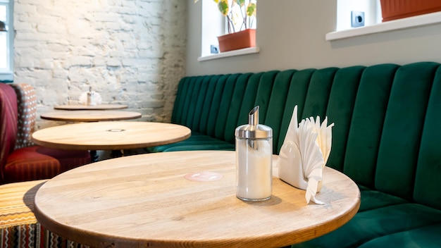 Un restaurante moderno y acogedor con sillas tapizadas de colores y cómodos sofás Hay servilletas y cubiertos en la mesa Mesa puesta para el almuerzo Desinfección en un establecimiento de comida rápida